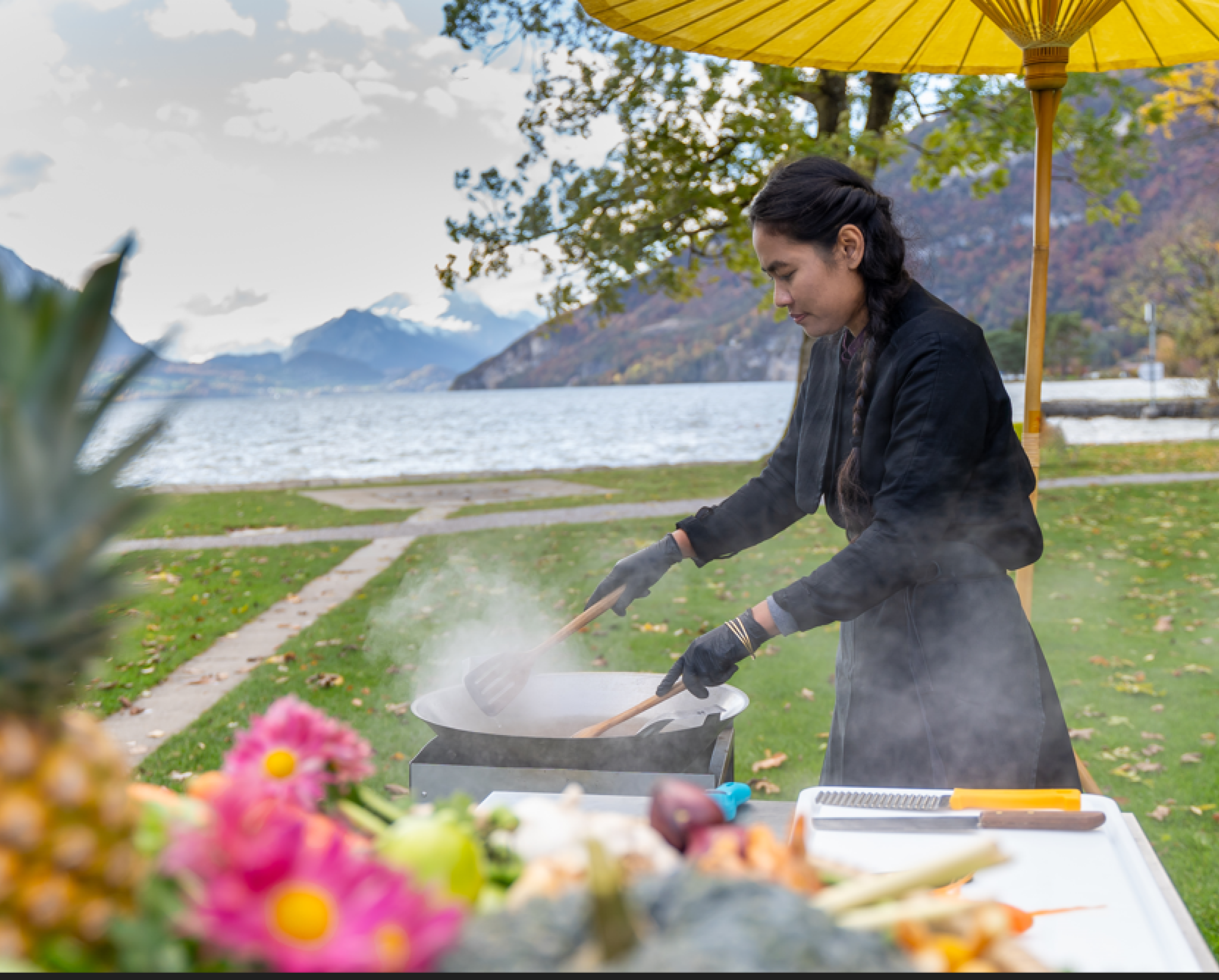 Frau, die am Ufer des Thunersees auf ihrer Outdoor-Küche thailändisch kocht. 